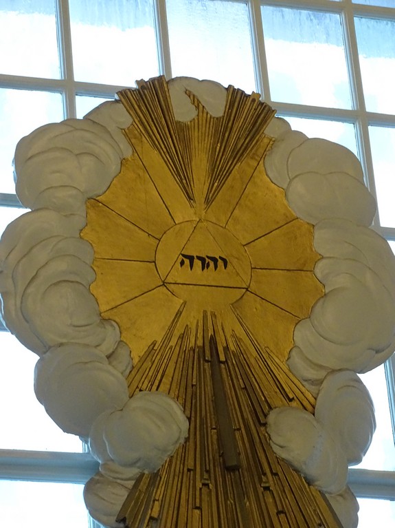 The front of the 9/11 Church (St. Paul's Chapel) has a sculpture representing "The Glory" as God's holy name in Hebrew. The light coming from the Tetragrammaton inside of clouds represents the "Glory" described in Exodus 24:16-17 and Ezekiel 1:28.